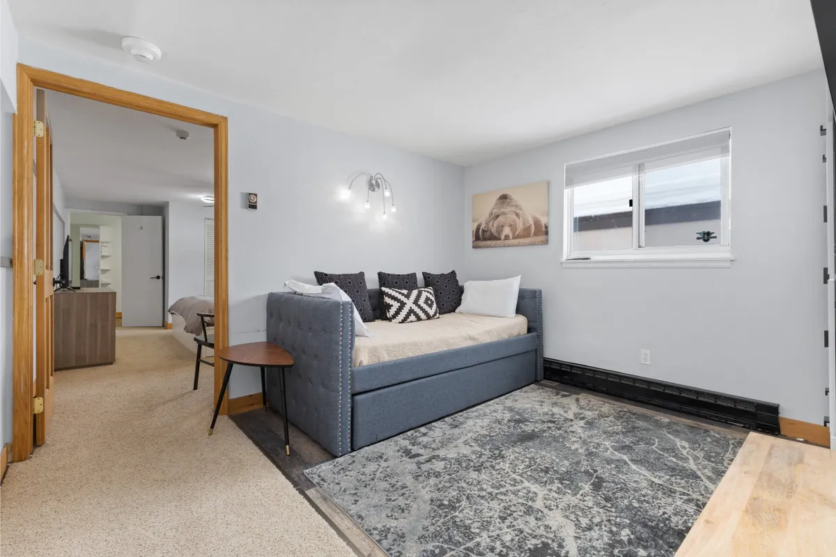 The image features a cozy daybed with decorative pillows positioned by a window, allowing natural light to fill the space. The inviting setting suggests a perfect spot for relaxing with a book or enjoying morning coffee while overlooking the outdoors.