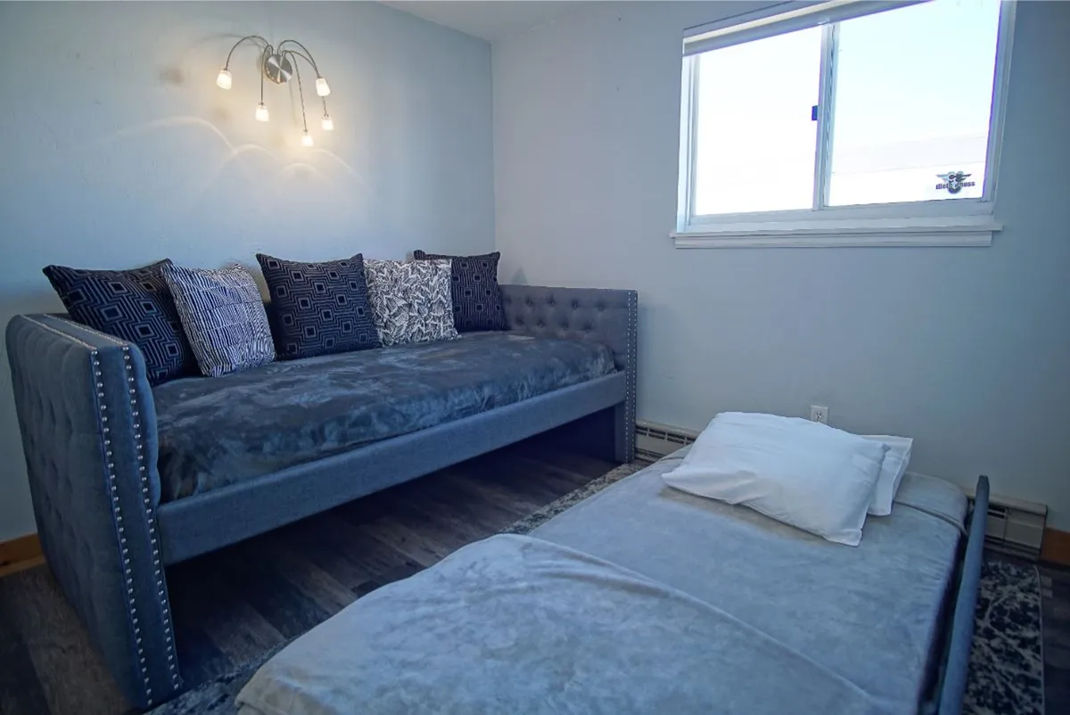 A light-filled corner with a daybed adorned with decorative pillows, set beside a window. The space exudes relaxation and is ideal for reading, napping, or unwinding after mountain adventures, emphasizing a sense of peace and retreat.